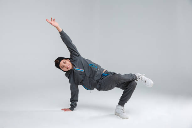 a cheerful little boy dressed in a gray tracksuit, actively dancing standing on one arm and one leg. gray background. - fashion model small one person happiness imagens e fotografias de stock