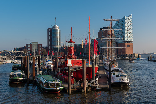 Photo is taken in the Hafencity region of Hamburg, Germany. Hafencity harbor, boats and yachts moored at the harbor, the famous Elbphilharmonie building are seen in the photo. The river in the photo is the Elbe River. Photo is taken on a sunny but cold winter day in January 2018.