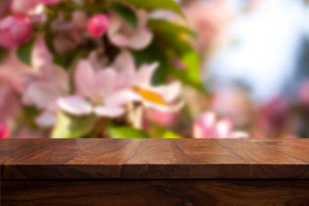 istock Empty top wooden table and floral blurred background 905575984