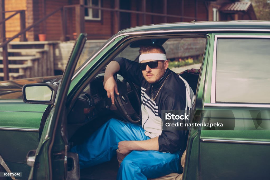 guy in the nineties sits behind the wheel of a car guy in the nineties sits behind the wheel of a car wearing sunglasses 1990-1999 Stock Photo