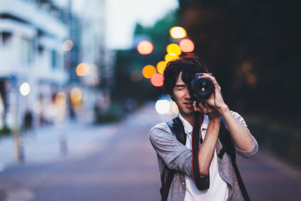 A young Japanese man is taking photos at night in Tokyo.