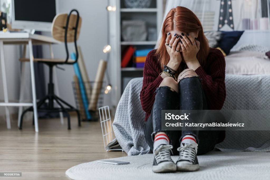 Girl with problems Girl sitting on the floor and crying because of problems at home with parents Teenager Stock Photo