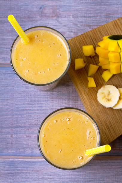 istock Mango banana smoothie on wooden background 905583234