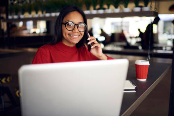 istock Cheerful afro american student in eyeglasses talking on mobile with friend while spending time in coffee shop, happy dark skinned freelancer getting job offer discussing details in phone conversation 905583498