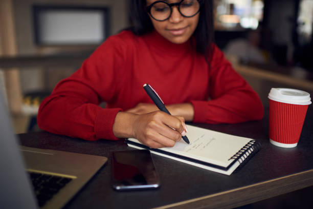 songeur étudiant américain afro dans idées de rédaction au journal à faire leurs devoirs en café, femme d’affaires qualifié, planification des processus de travail création liste des tâches pour démarrage notant points objectifs de lunettes de vue - lundi noir chinois photos et images de collection