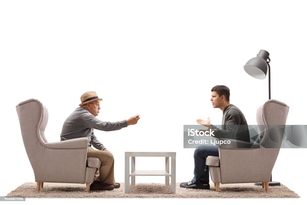 Mature man and a young guy seated in armchairs arguing Mature man and a young guy seated in armchairs arguing isolated on white background Two People Stock Photo