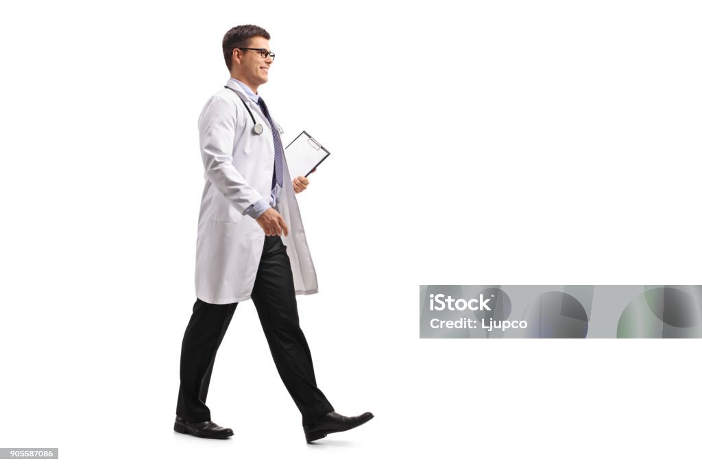 Doctor with a clipboard walking Full length profile shot of a doctor with a clipboard walking isolated on white background Doctor Stock Photo
