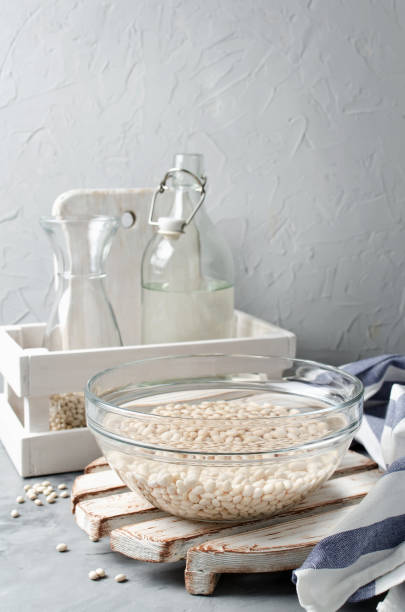 haricots blancs trempés dans l’eau dans un bol en verre - soybean bean drenched textured photos et images de collection