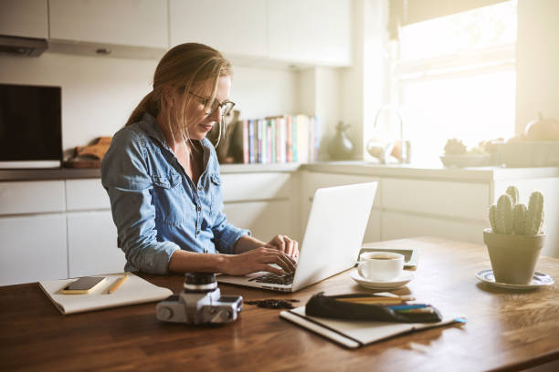 istock Young woman sitting in her kitchen working on a laptop 905595170