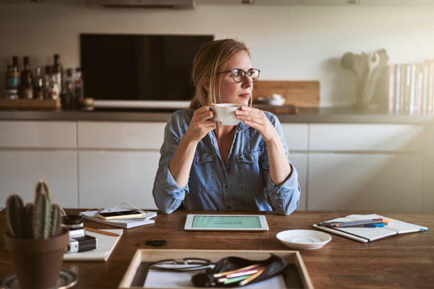 istock Young woman drinking coffee and thinking while working from home 905595372