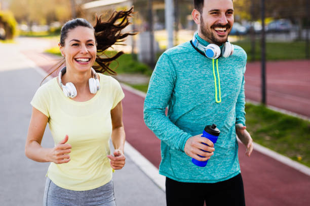 istock Young attractive couple running outside on sunny day 905600596