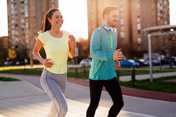 istock Young attractive couple running outside on sunny day 905602770