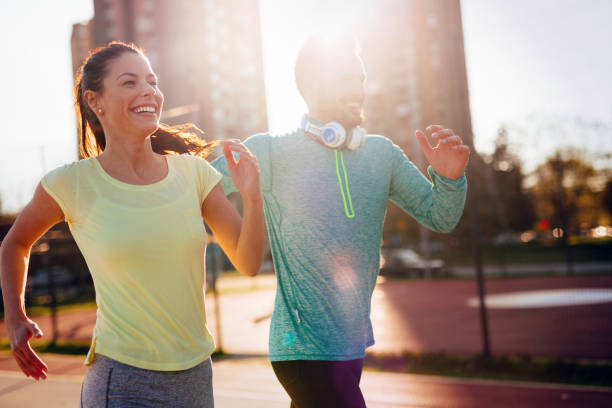 istock Young attractive couple running outside on sunny day 905602898