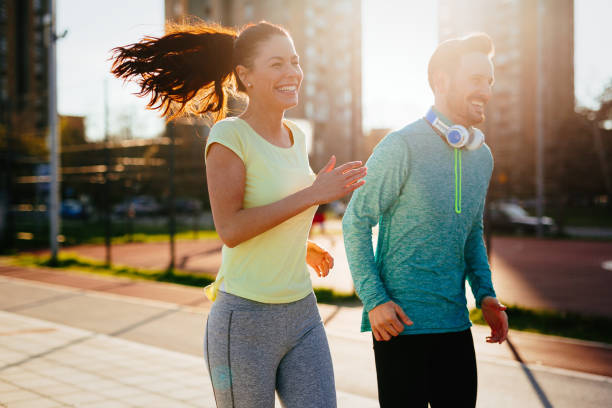 istock Young attractive couple running outside on sunny day 905603068