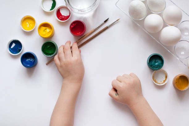istock Children's hands paint Easter eggs. The child is drawing, step by step 905604034