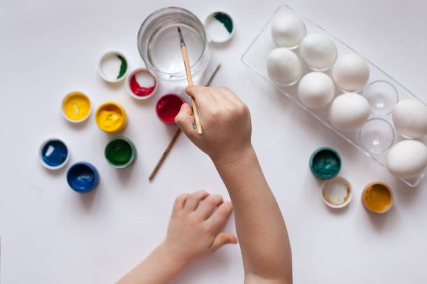 istock Children's hands paint Easter eggs. The child is drawing, step by step 905604042