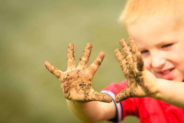 istock Child playing outdoor showing dirty muddy hands. 905607376