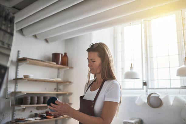 istock Artisan inspecting a new ceramic piece in her pottery workshop 905613110