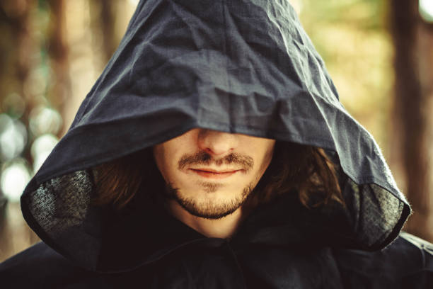 A creepy man in a black hood in the forest