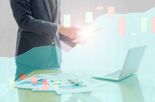 istock Double exposure of Young business man with suit working on digital tablet while standing with stock equity chart and candle stick graph. 905620174