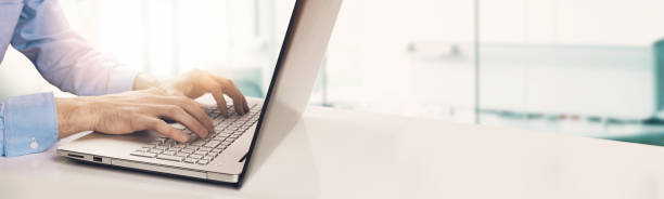 modern businessman typing on laptop keyboard in bright sunny office. copyspace - contemporary laptop human hand computer keyboard imagens e fotografias de stock