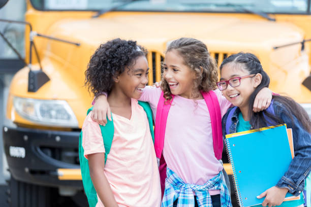 istock Three schoolgirls greet each other after long summer 905633190