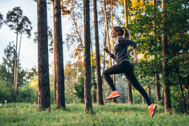 joven atleta femenina a correr por el bosque. jogger haciendo entrenamiento físico de mañana. - corredora de footing fotografías e imágenes de stock