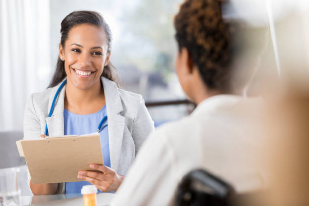 female doctor prescribes medication to a wheelchair-bound patient - cheerful doctor prescribes professional occupation imagens e fotografias de stock