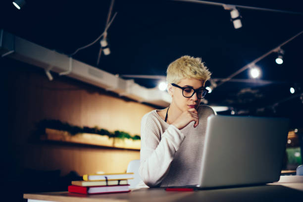 istock Clever trendy dressed female student working productively on coursework reading information on laptop,skilled creative designer analyzing plan for task pondering on problem solution in loft interior 905637938