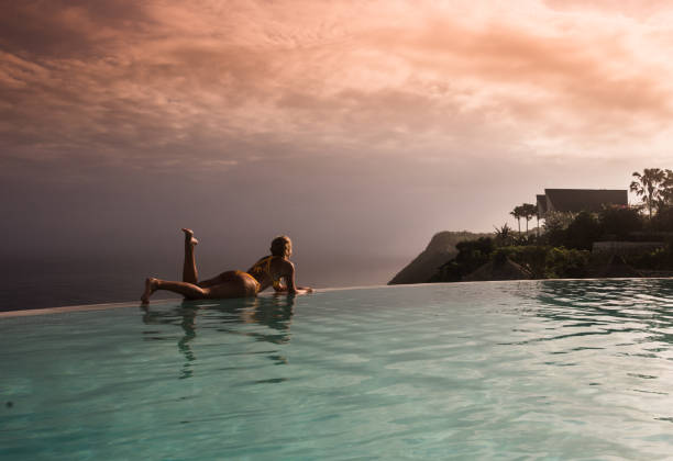 istock Woman in yellow bikini relaxing on tropical infinity pool at sunset. 905643790