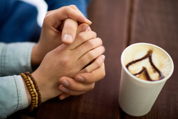istock Couple touching hands in coffee shop 905647538
