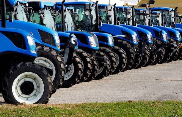 Close up of brand new blue tractors,  side by side, in a long line Close up of brand new blue tractors,  side by side, in a long line . agricultural machinery stock pictures, royalty-free photos & images