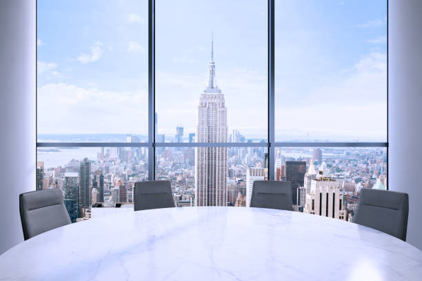 istock Office interior with large round desk and chairs with view at Empire state building 905660010