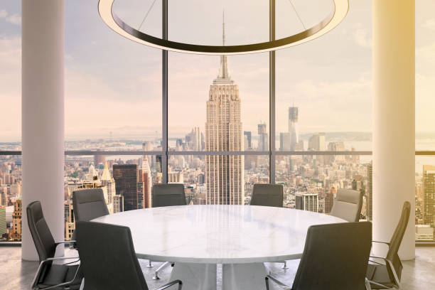 istock Office interior with large round desk and chairs with view at Empire state building 905660016