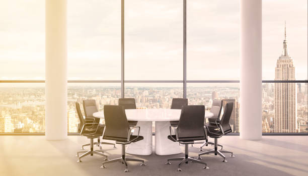 Office interior with large round desk and chairs with view at Empire state building