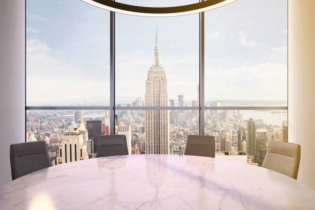 istock Office interior with large round desk and chairs with view at Empire state building 905660038