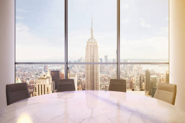 istock Office interior with large round desk and chairs with view at Empire state building 905660046
