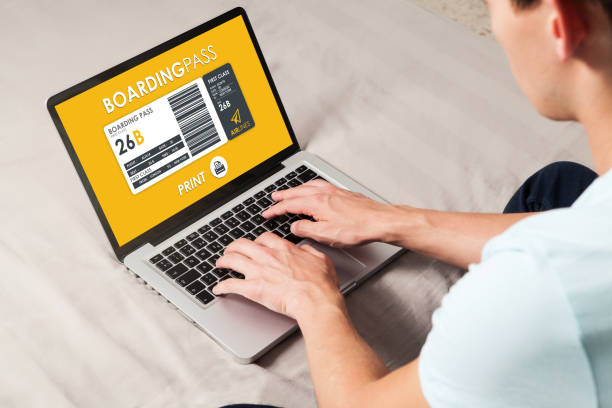 istock Boarding pass to print in a laptop screen. Man using a laptop to print flight boarding pass at home. 905666810