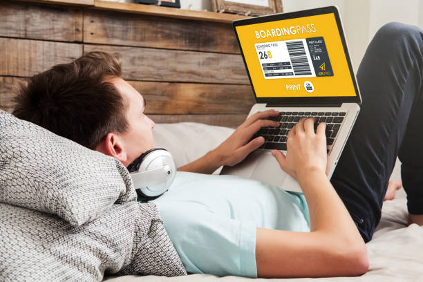 istock Man using a laptop computer to print flight boarding pass at home. 905666882