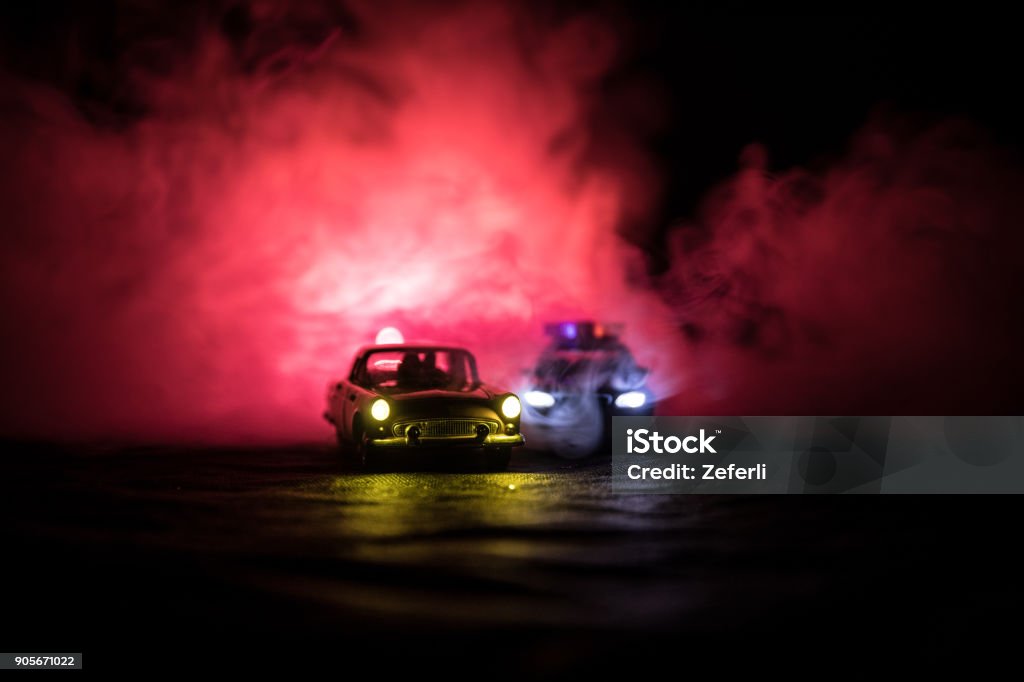 Toy BMW Police car chasing a Ford Thunderbird car at night with fog background. Toy decoration scene on table . Selective focus "u2013 11 JAN 2018, BAKU AZERBAIJAN 4x4 Stock Photo
