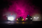 Toy BMW Police and Toyota FJ Cruiser cars chasing a Ford Thunderbird car at night with fog background. Toy decoration scene on table .