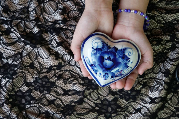 Box in the shape of a heart in his hands. Gzhel. The view from the top. Valentine's day. A symbol of love. Valentine. The background is made of cloth. Design element.