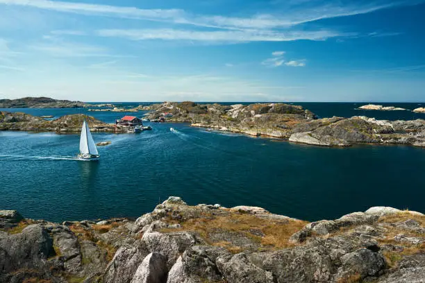Sea landscape with sailboat and rocky coastline on the South of Sweden. Southern coastline of Sweden with view at sailing-ships and rocky islands.