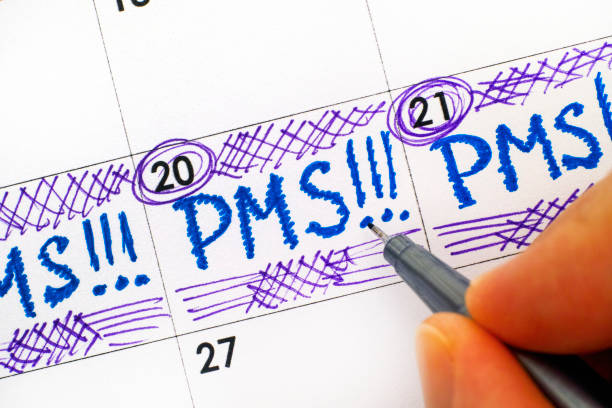 Woman fingers with pen writing reminder PMS in calendar. Woman fingers with pen writing reminder PMS in calendar. Close-up. pms photos stock pictures, royalty-free photos & images