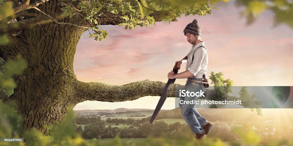 Cutting the branch your sitting on A young man making a mistake by self sabotaging himself. Mistake Stock Photo