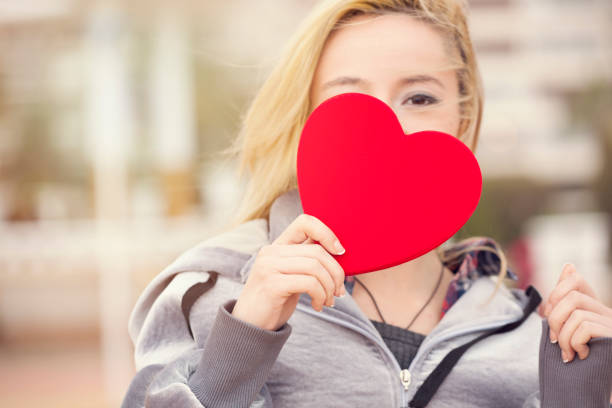 Young woman holding heart-shaped paper