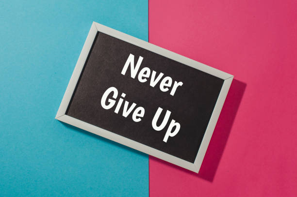 istock Never give up - text on chalkboard on blue and pink bright background. 905706476