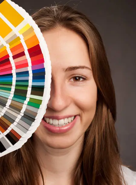young woman holding a pantone palette on a gray background