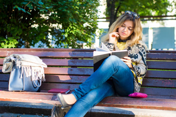 istock Young woman reading a book and relaxing at the park 905714608