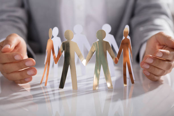 istock Businessperson Hand Protecting Paper Cut Out Figure On Table 905715548